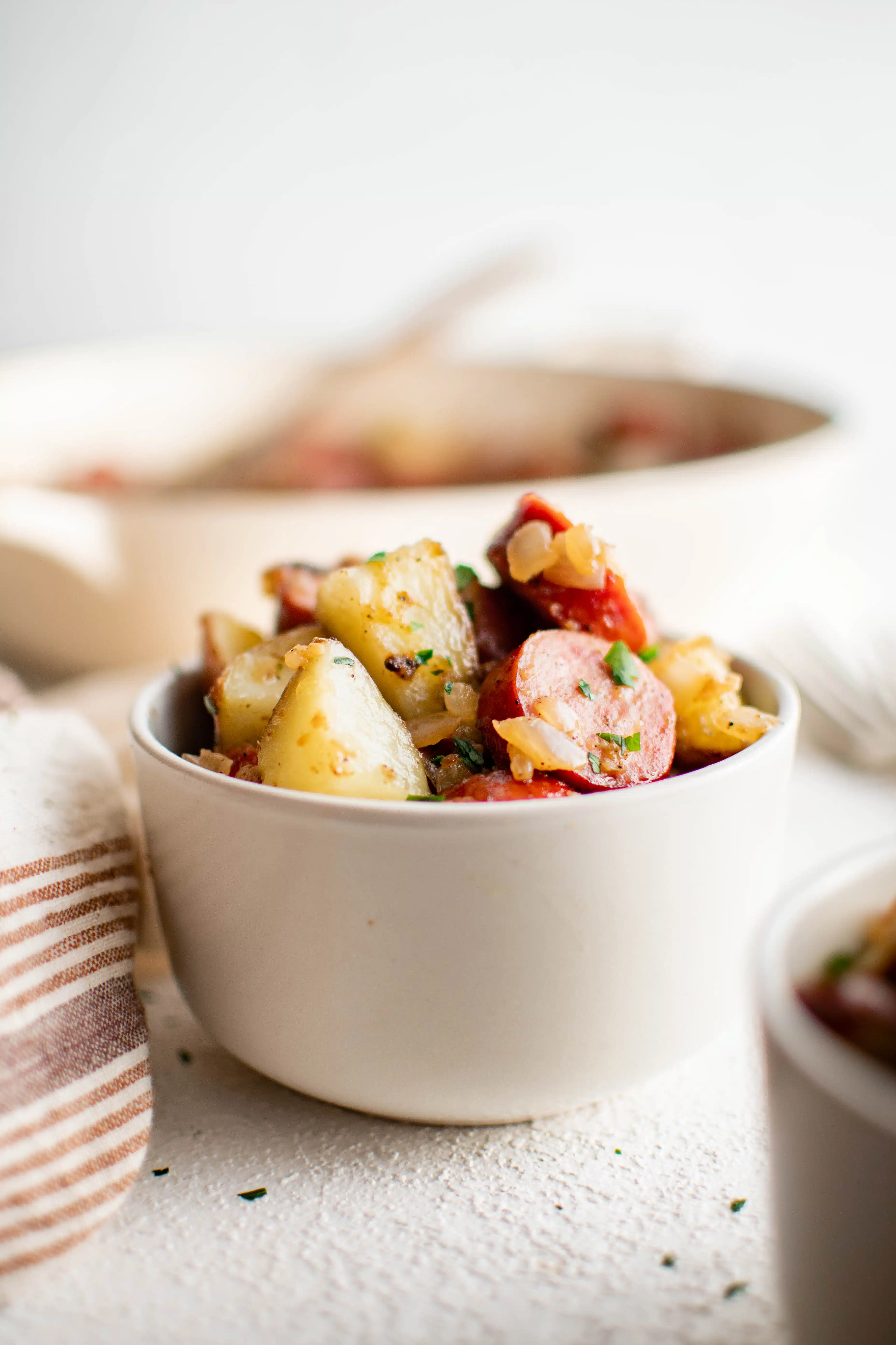 White bowl filled with an easy dinner of kielbasa and potatoes.