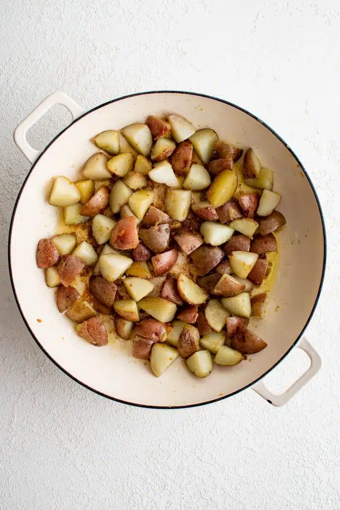 Large pan filled with tender cooked bite-size pieces of red potatoes.