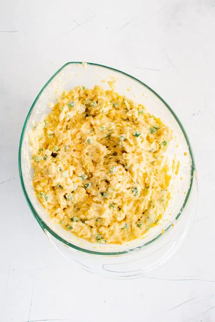 Large glass mixing bowl filled with Mexican cornbread batter.