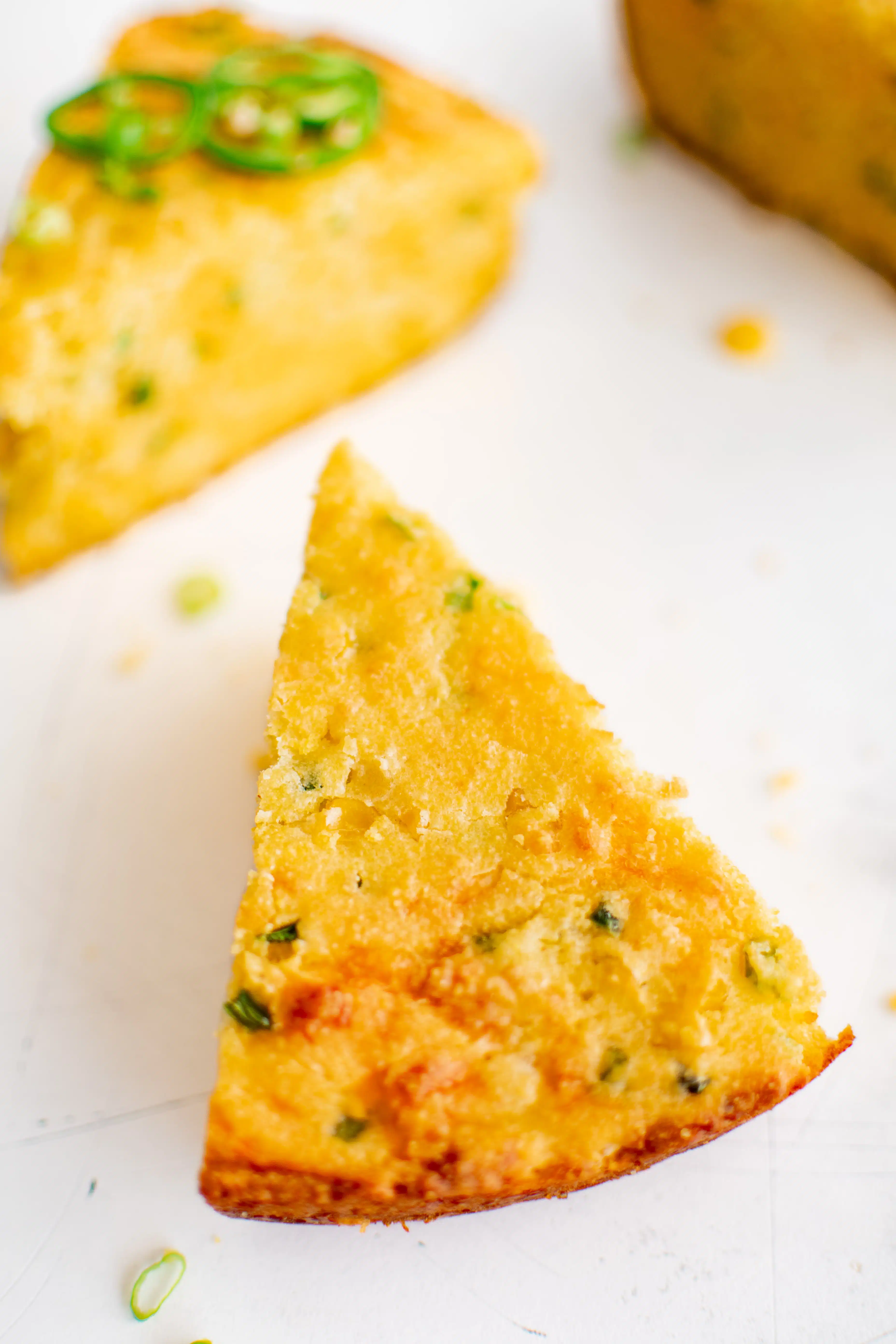 Large slice of Mexican cornbread with golden brown edges and specks of green from jalapeño.