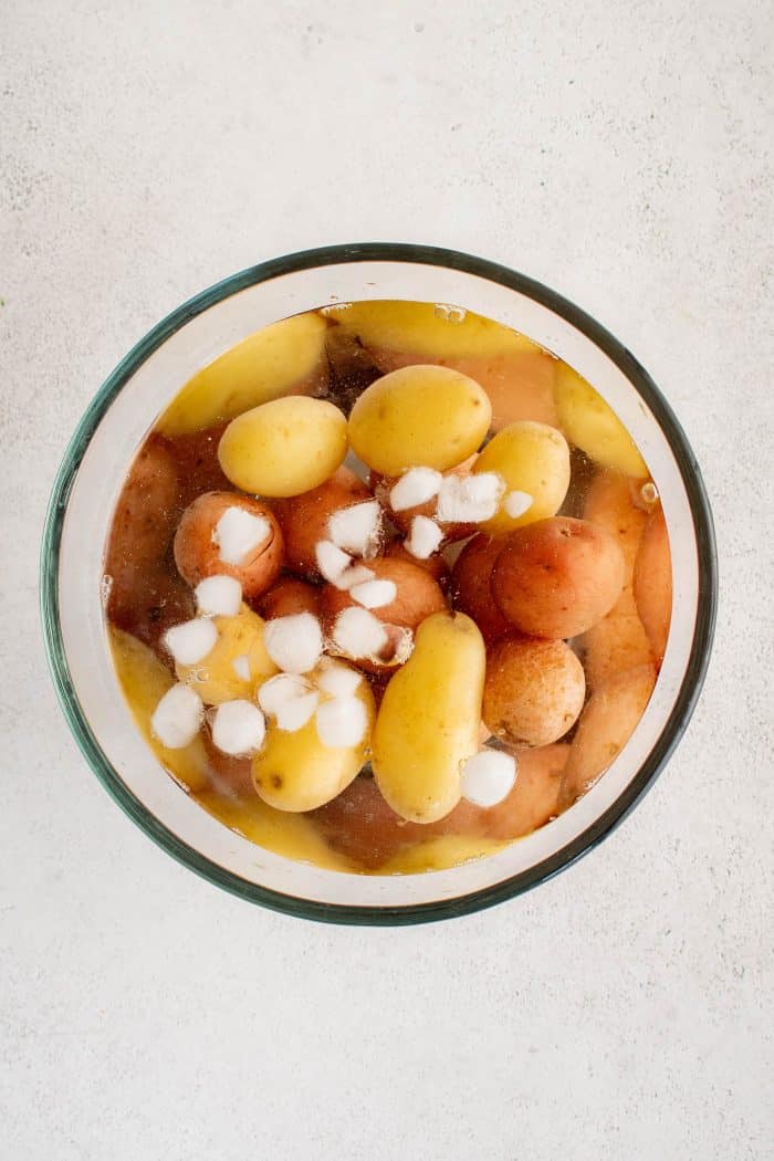 Glass bowl filled with small potatoes in ice water.