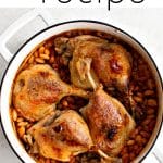 Overhead view of a white Dutch oven filled with cassouletโa traditional French dishโshowing four browned duck legs nestled on top of a bed of baked white beans.