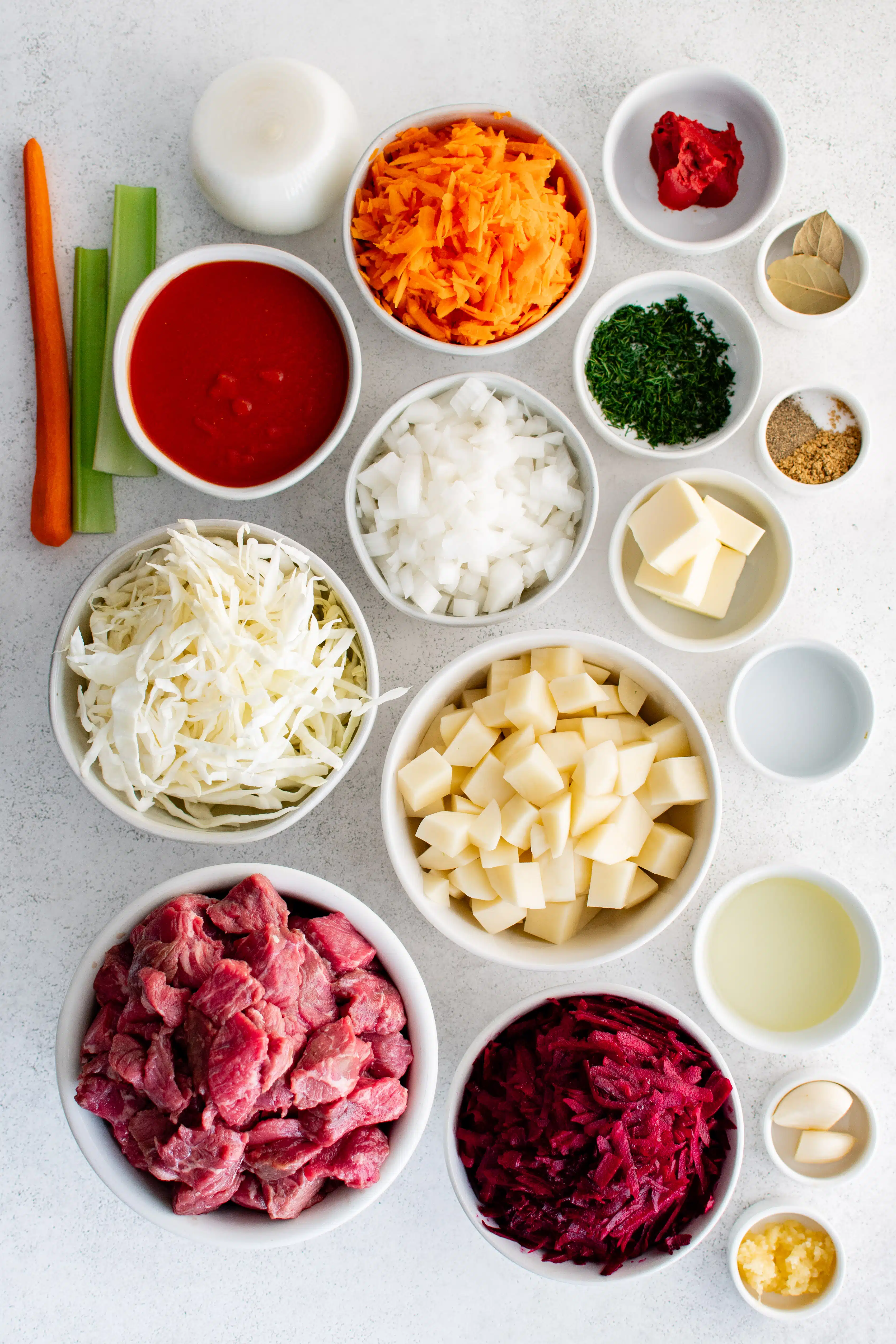Ingredients needed to make traditional Ukrainian borscht soup in individual measuring cups and ramekins.