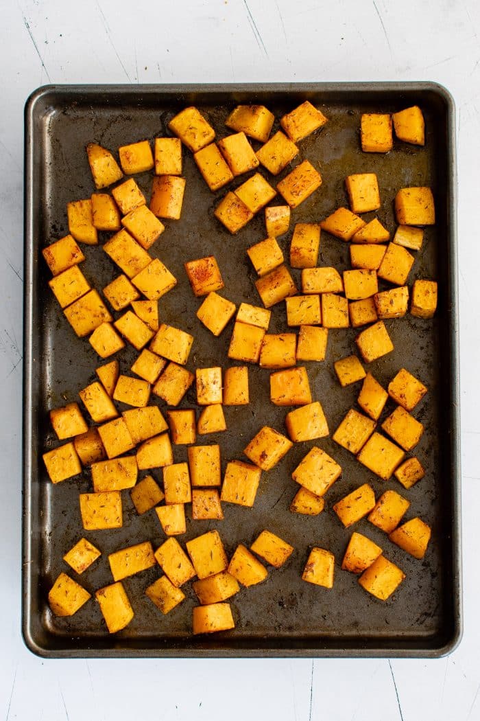 Tender roasted butternut squash cubes on a large baking sheet.