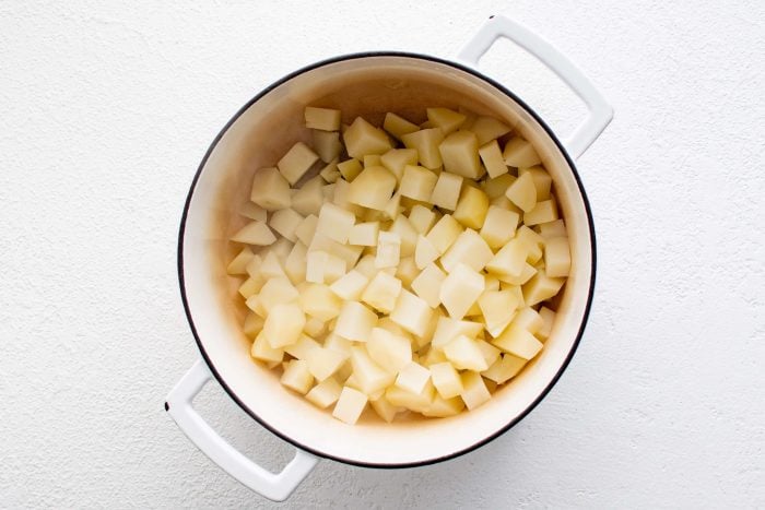 Large pot filled with small cubes of boiled and drained potatoes.
