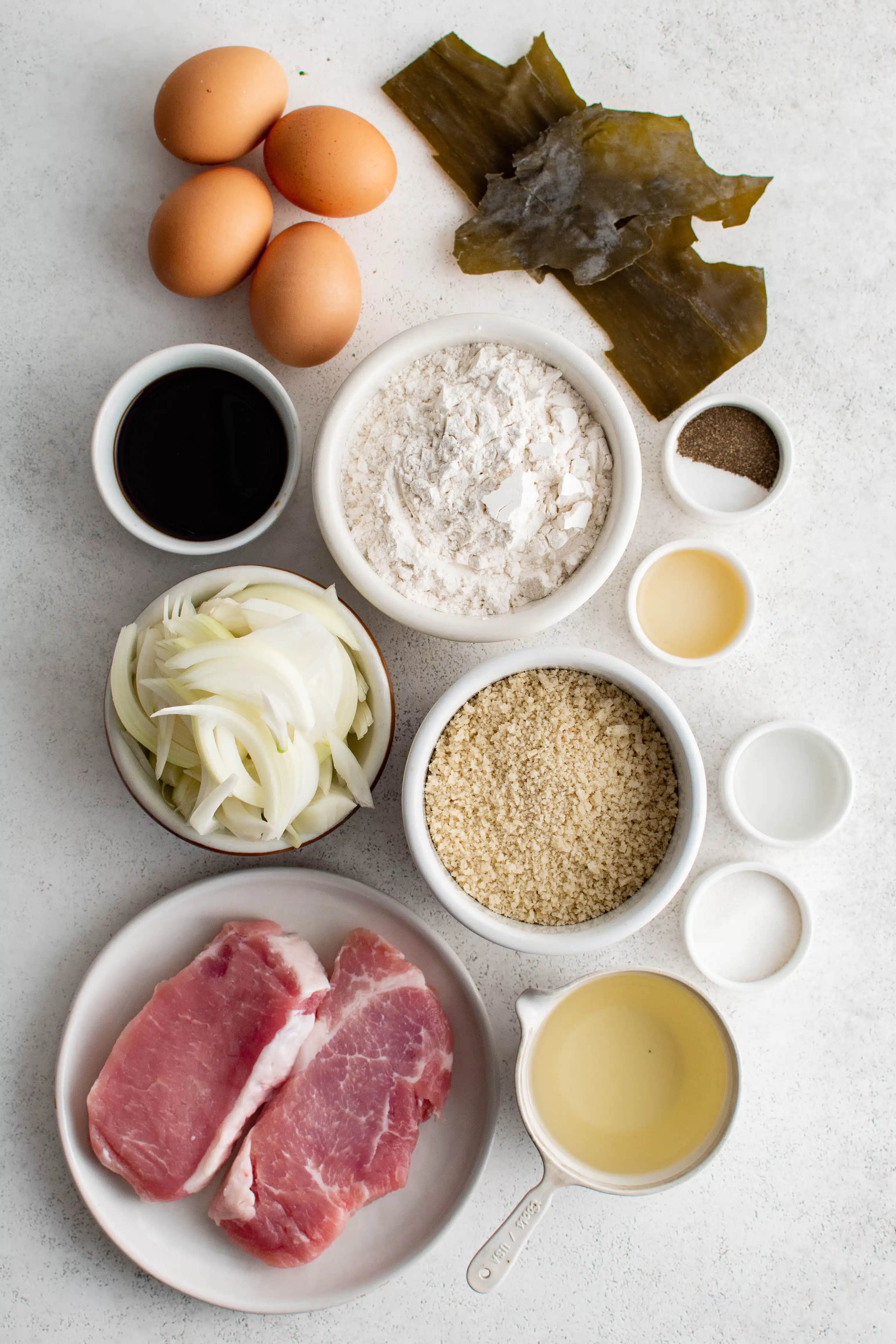 Ingredients needed to make Katsudon in a bowl in individual measuring cups and ramekins.