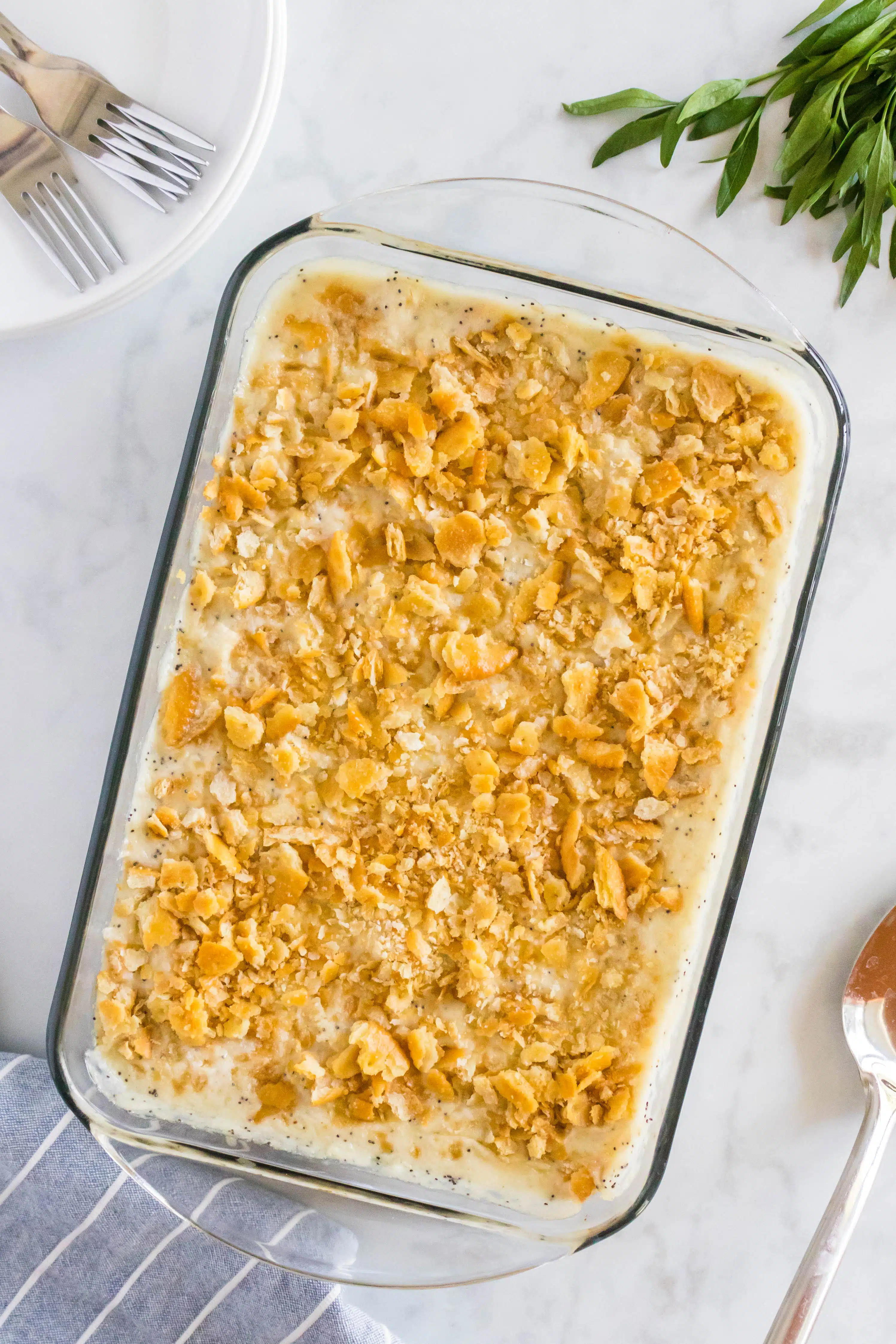 Overhead image of a large glass baking dish filled with creamy poppy seed chicken casserole topped with golden buttery crumbled Ritz crackers.