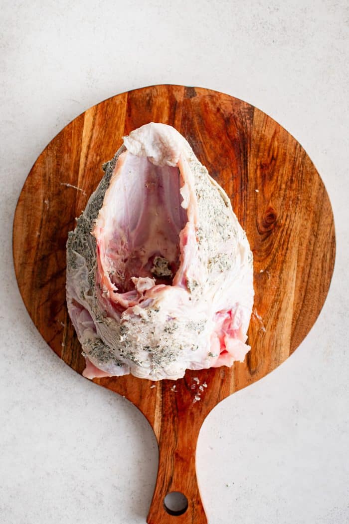 The underside of the turkey breast showing herb butter spread across the exposed meat.