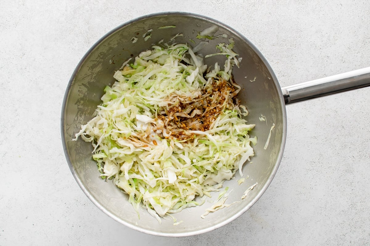 Stir fry sauce poured over shredded cabbage in a wok.
