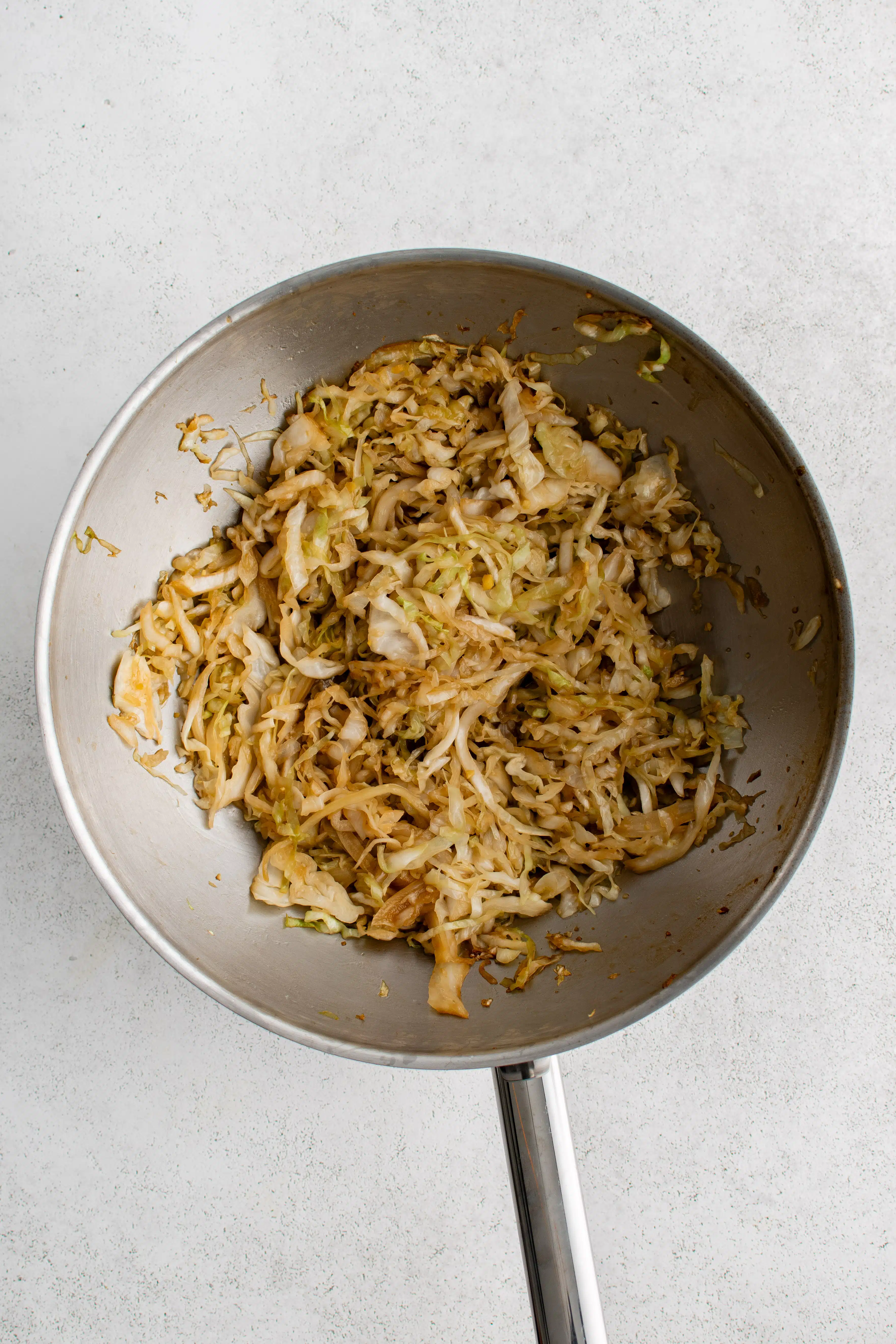 Large stainless steel wok filled with cooked stir-fried cabbage.