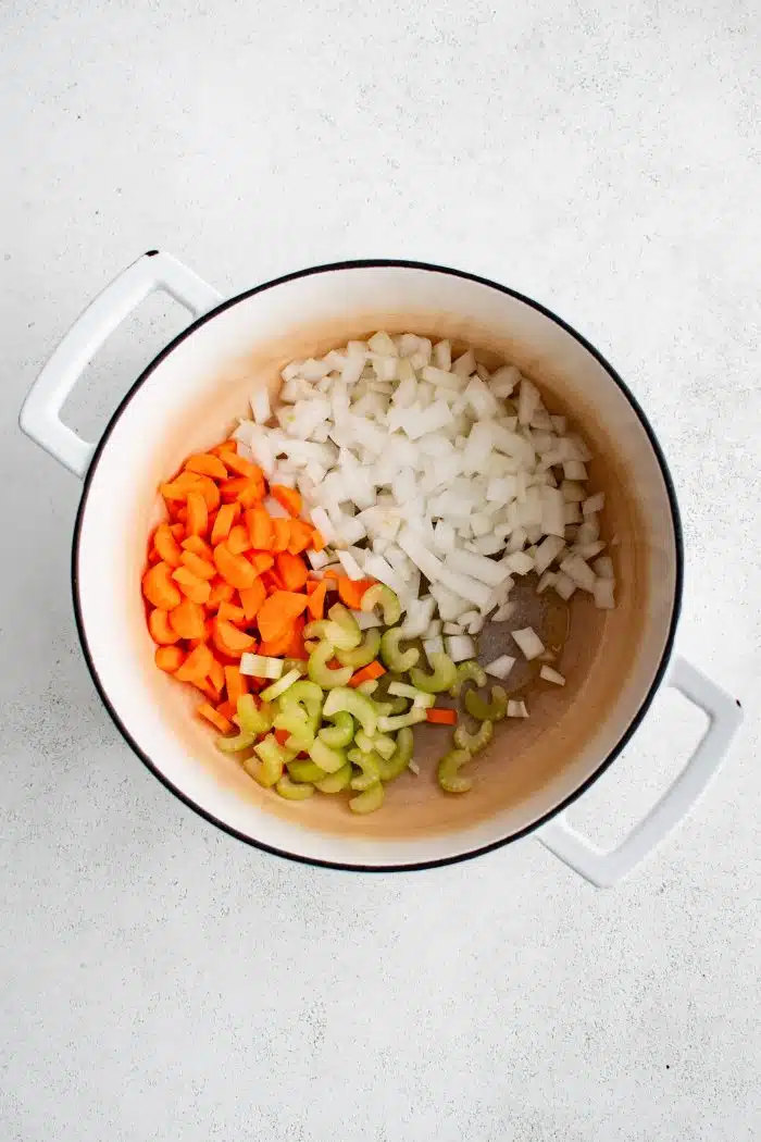 Raw diced onion, carrot, and celery in a large Dutch oven.