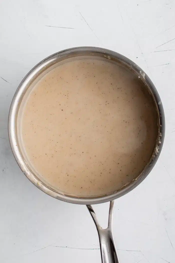 Medium saucepan filled with white pepper gravy.