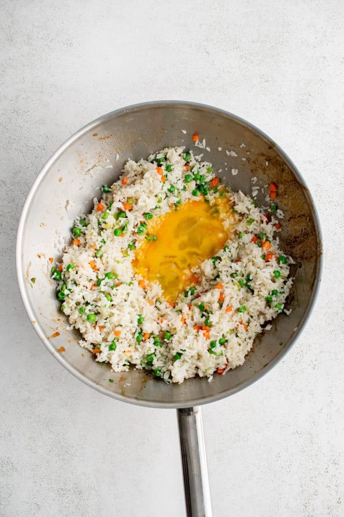 Scrambled egg added to stir-fried rice with peas, carrots, green onion, and garlic.