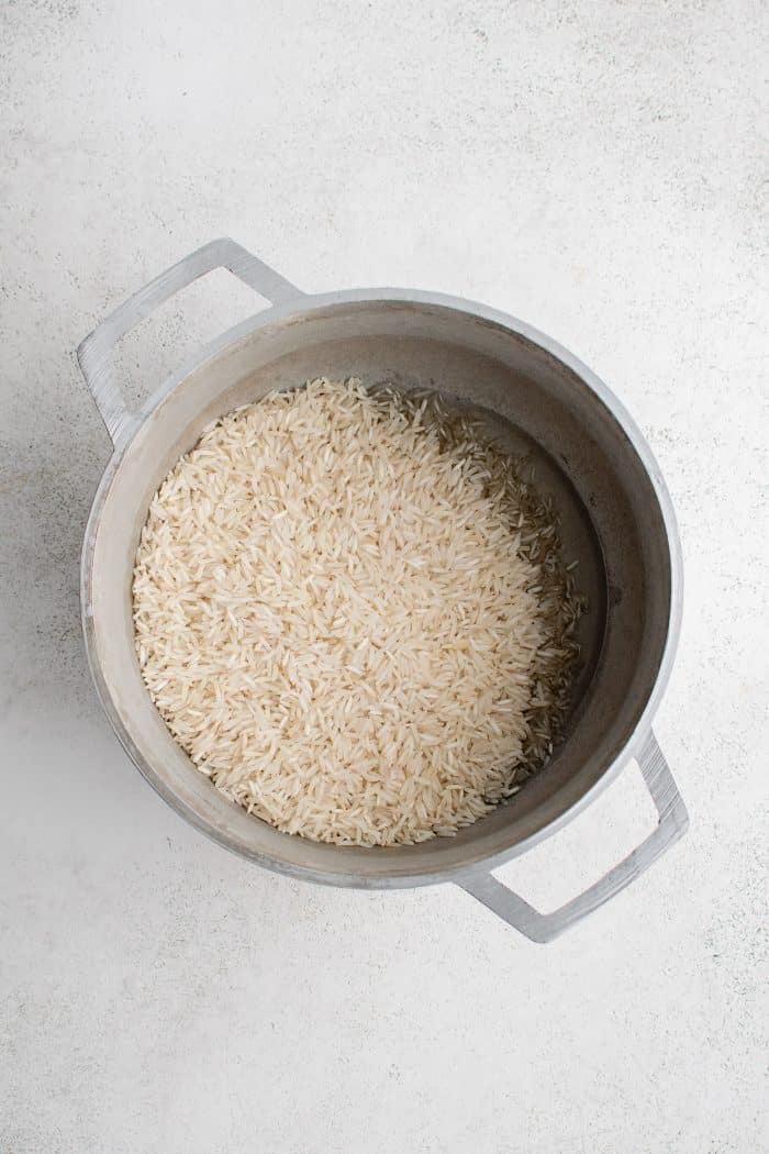 Large white cooking pot with vegetable oil and basmati rice.