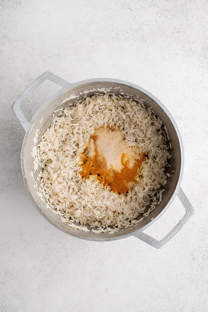 Toasted basmati rice and spices in a large white pot.