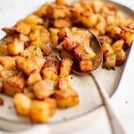 Crispy, golden, and well-seasoned breakfast potatoes cooked in the air fryer served on a medium-sized white oval serving platter.