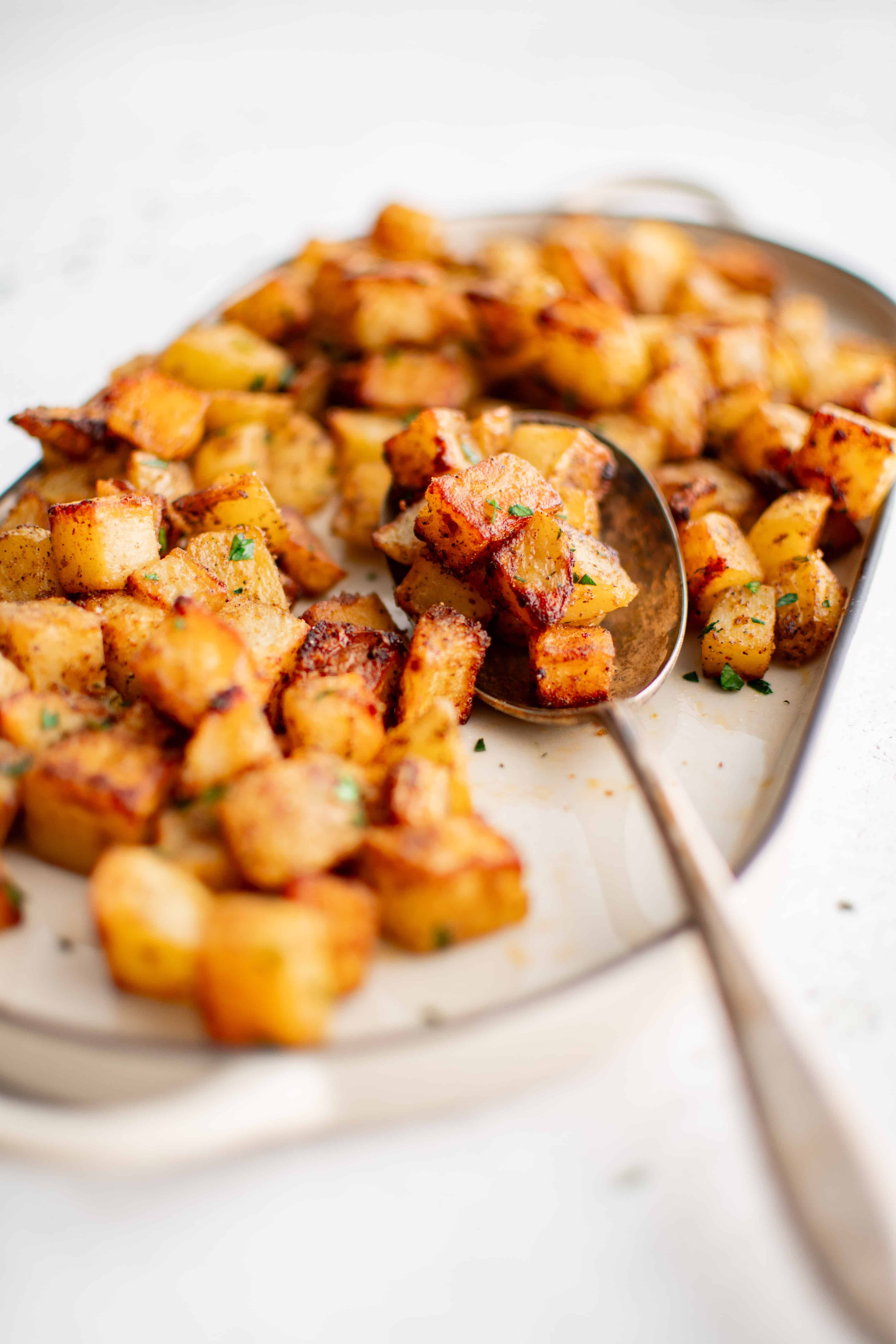 Crispy, golden, and well-seasoned breakfast potatoes cooked in the air fryer served on a medium-sized white oval serving platter.