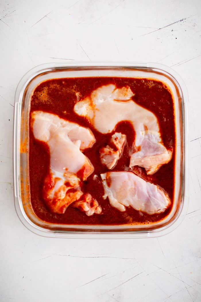 Boneless skinless chicken thighs marinating in homemade al pastor marinade.