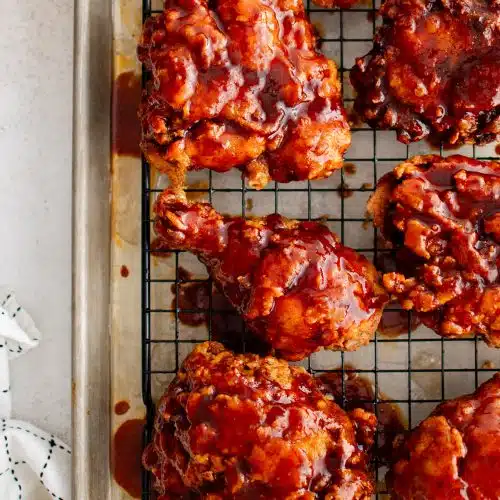 Crispy pieces of Nashville hot chicken on a baking rack set inside a large rimmed baking sheet.