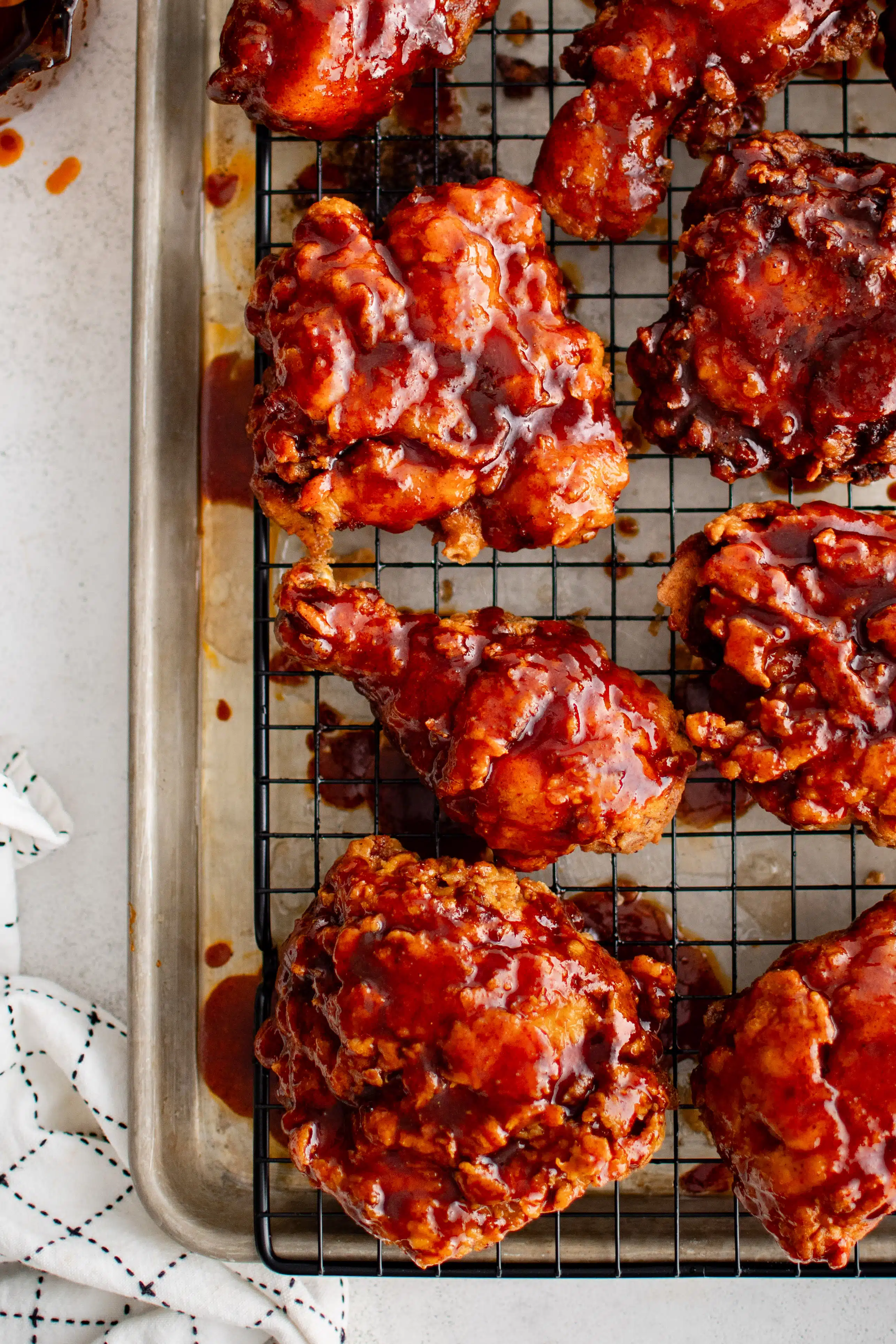Crispy pieces of Nashville hot chicken on a baking rack set inside a large rimmed baking sheet.