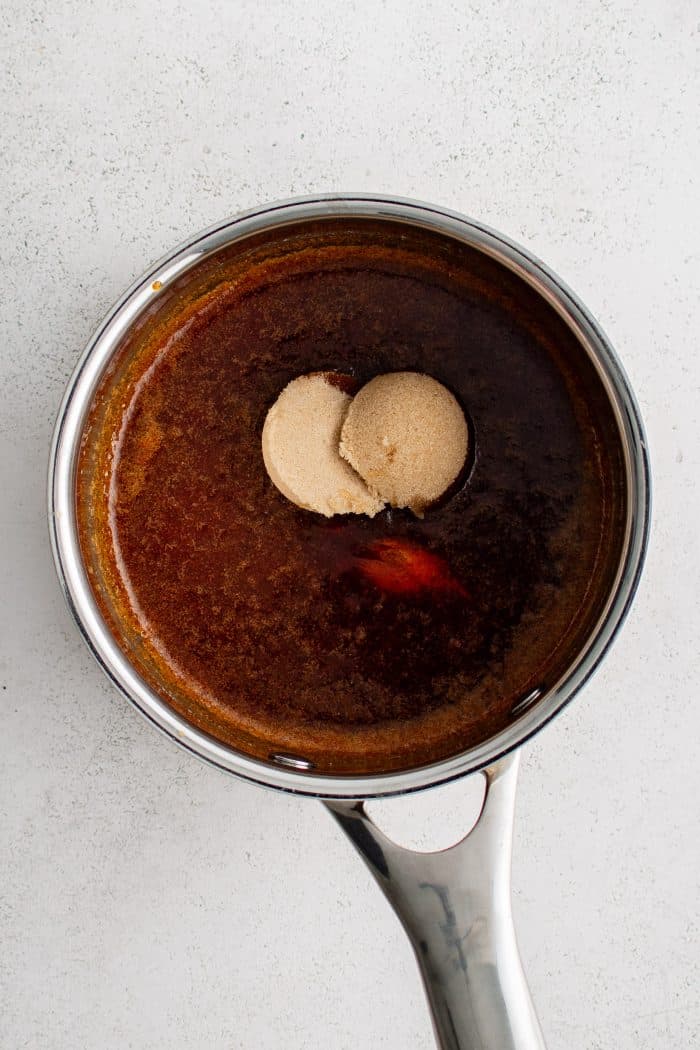 Brown sugar, honey, and vinegar added to a small sauce pot filled with garlic powder, onion powder, paprika, cayenne powder, and salt whisked in melted butter.