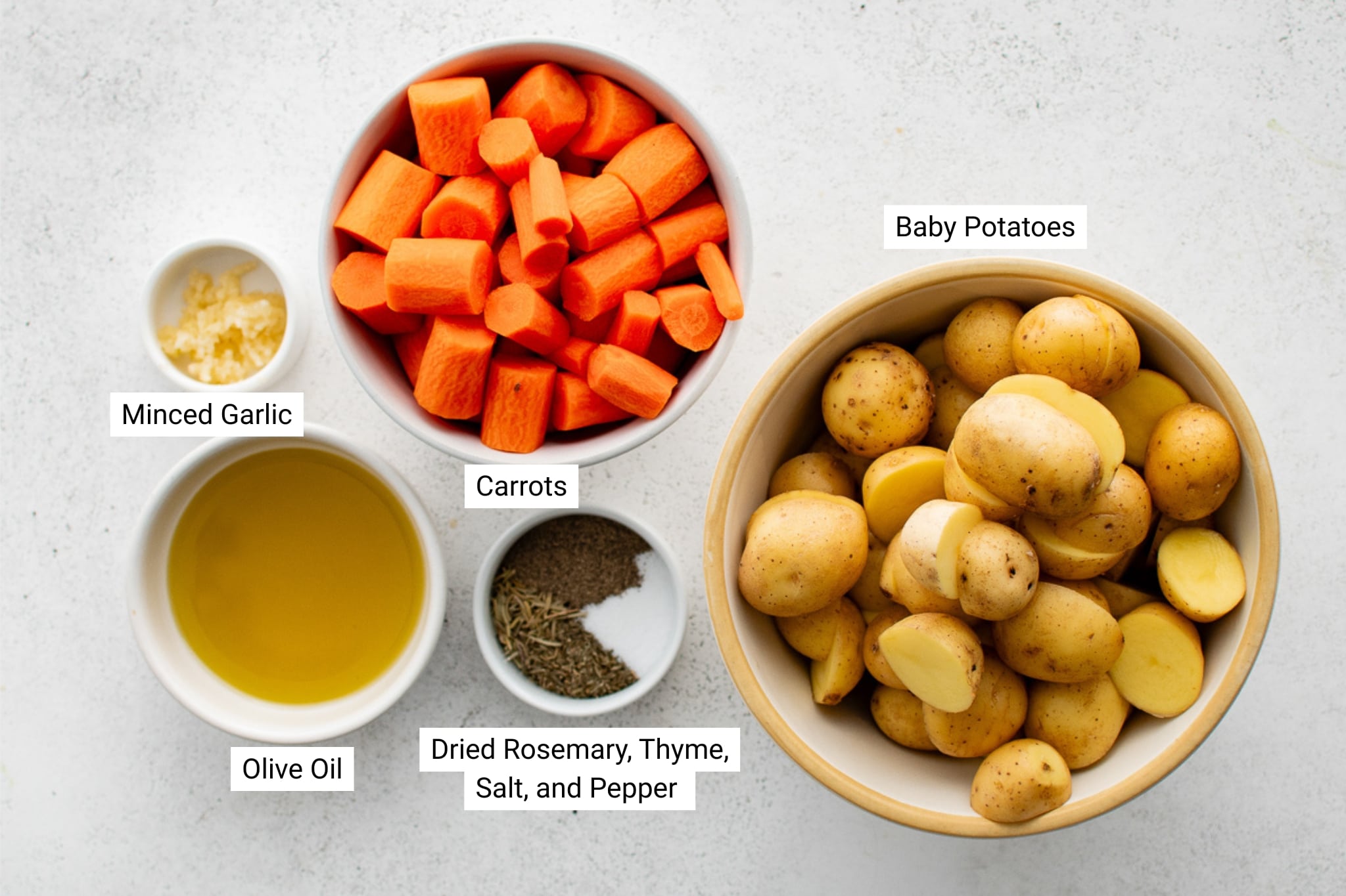 Label ingredient image for roasted potatoes and carrots including baby potatoes, carrots, garlic, olive oil, and dried herbs