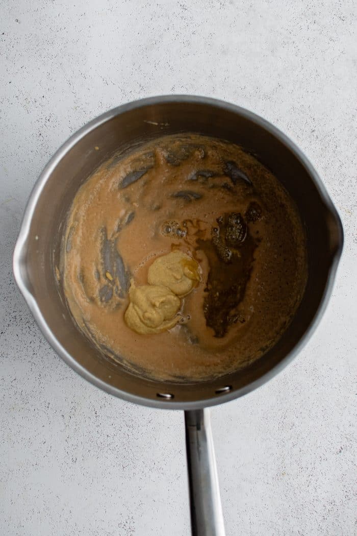 Small saucepan with honey and mustard added to butter and flour roux.