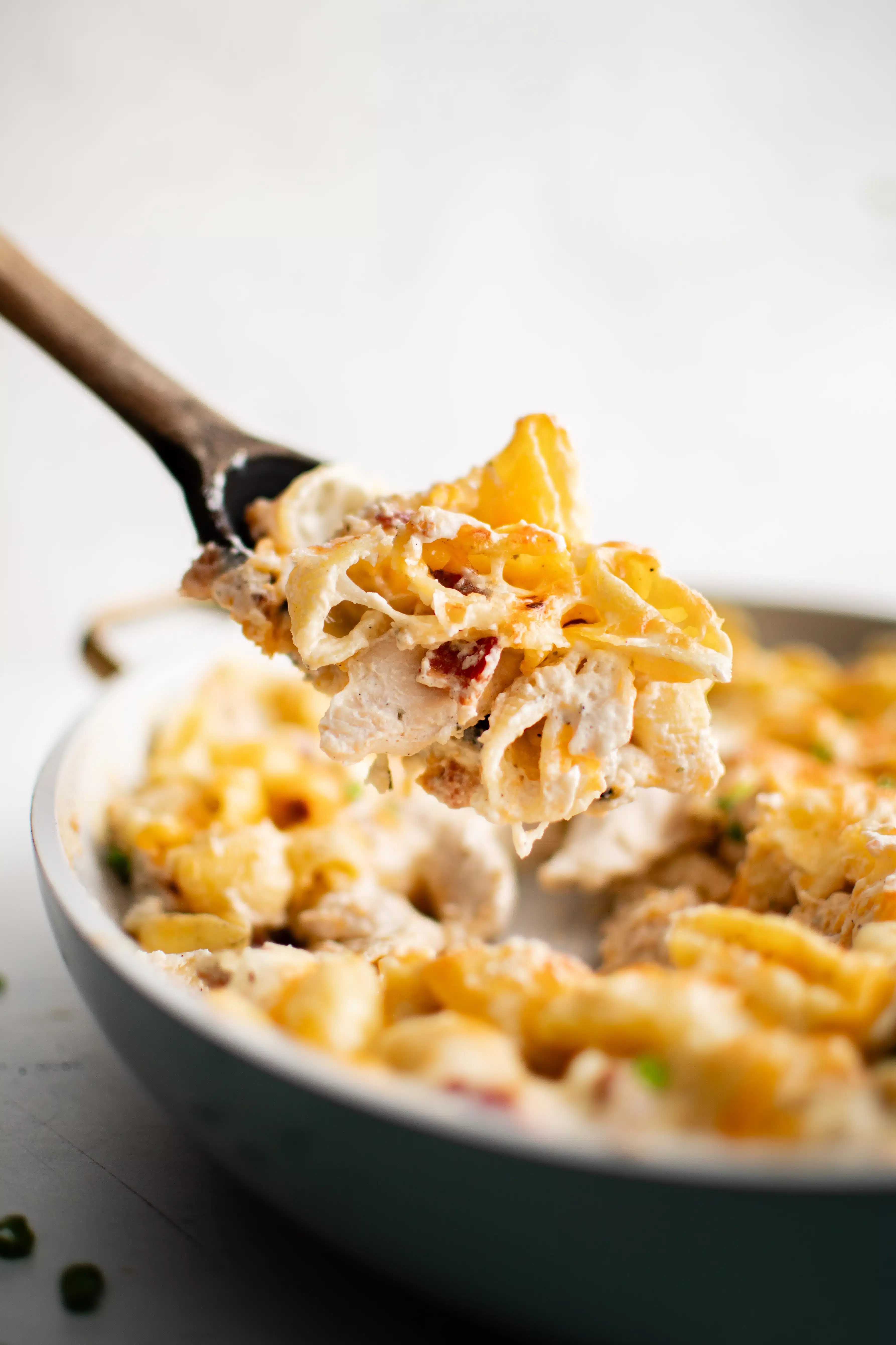 Large wooden spoon filled with crack chicken casserole made with cheese and noodles.