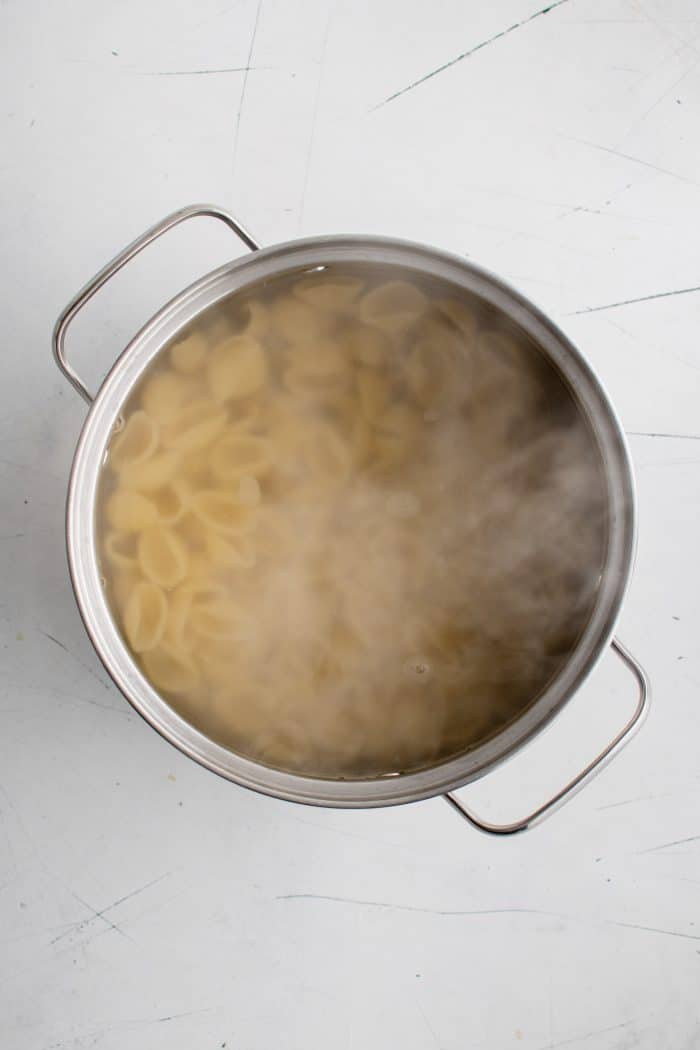 Shell pasta cooking in a large pot of boiling water.
