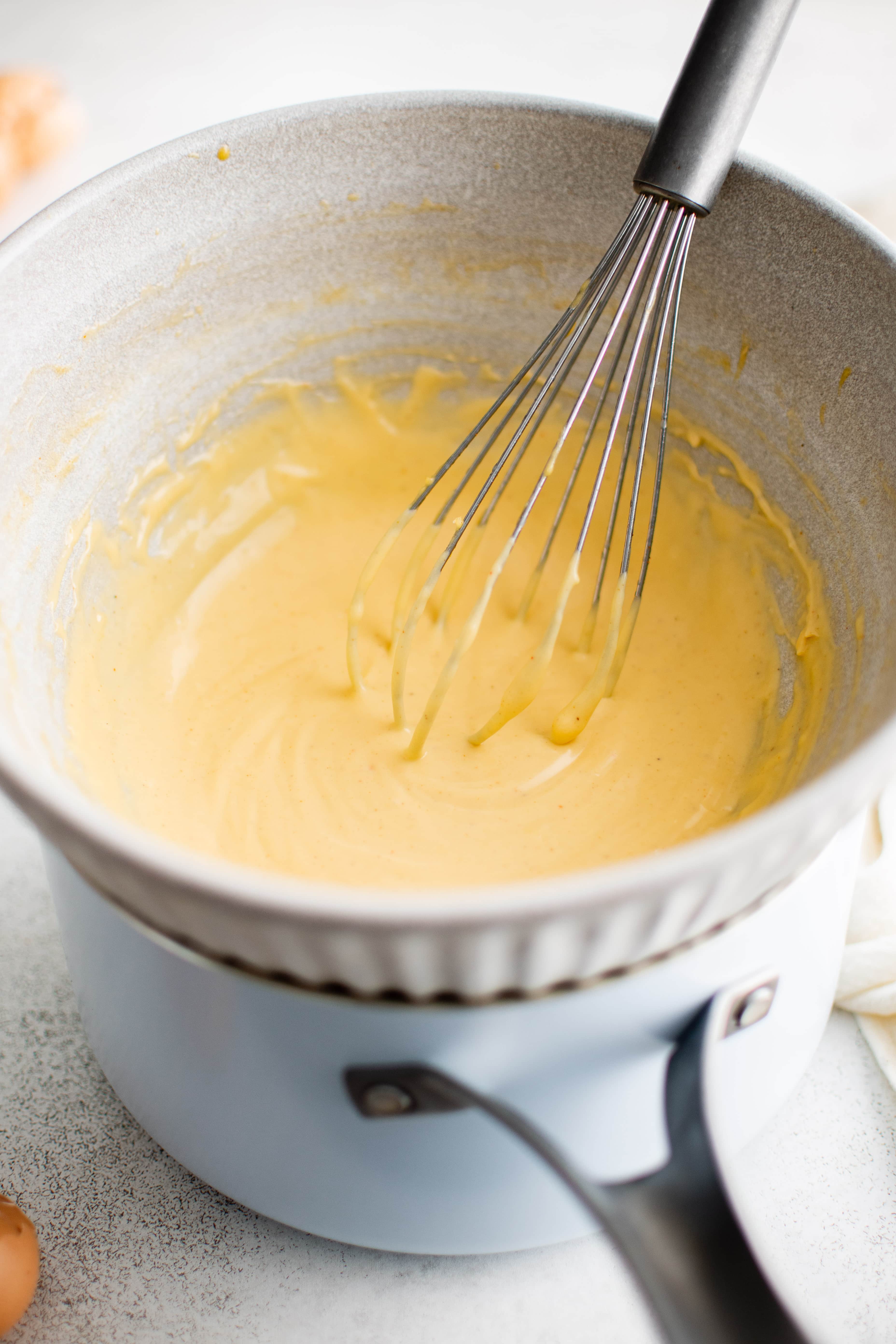 Golden yellow hollandaise sauce in a bowl set in a double broiler.