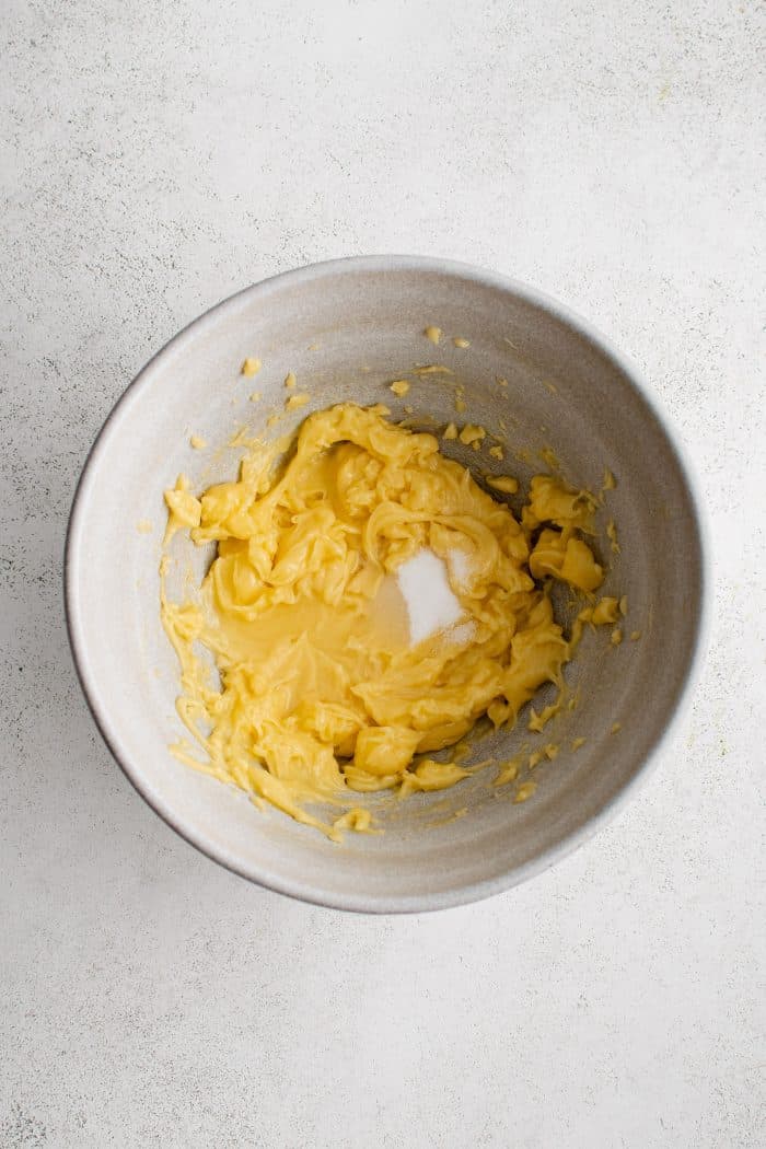 Fresh lemon juice, vinegar, sugar, and salt, added to fully incorporated egg yolks and light olive oil in a medium mixing bowl.