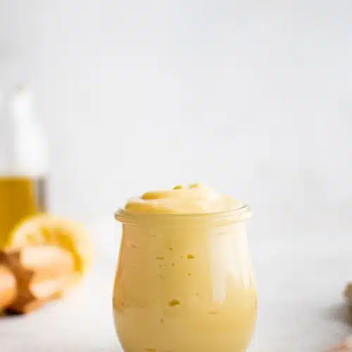 Small glass jar filled with creamy, light yellow colored homemade mayonnaise.