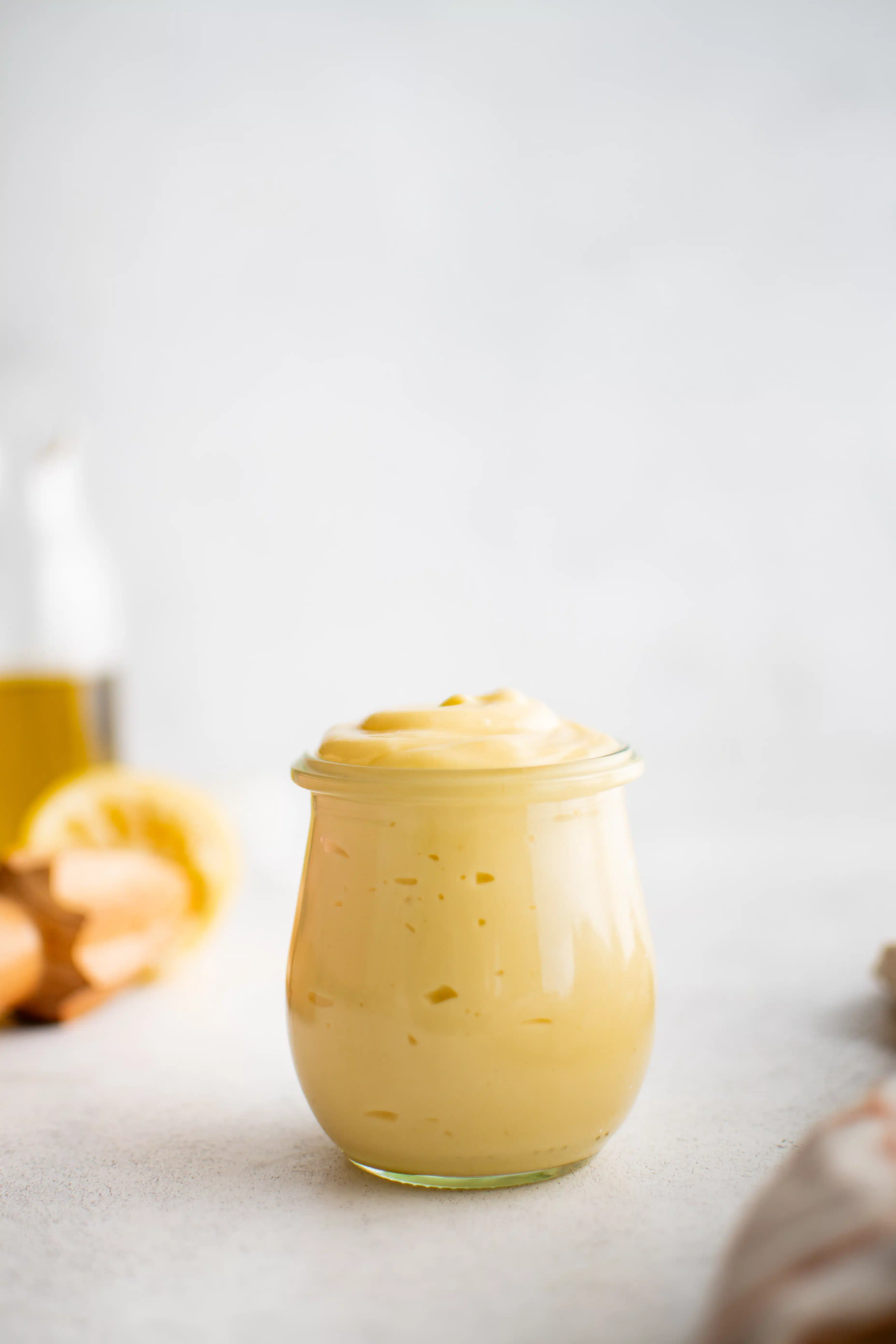 Small glass jar filled with creamy, light yellow colored homemade mayonnaise.