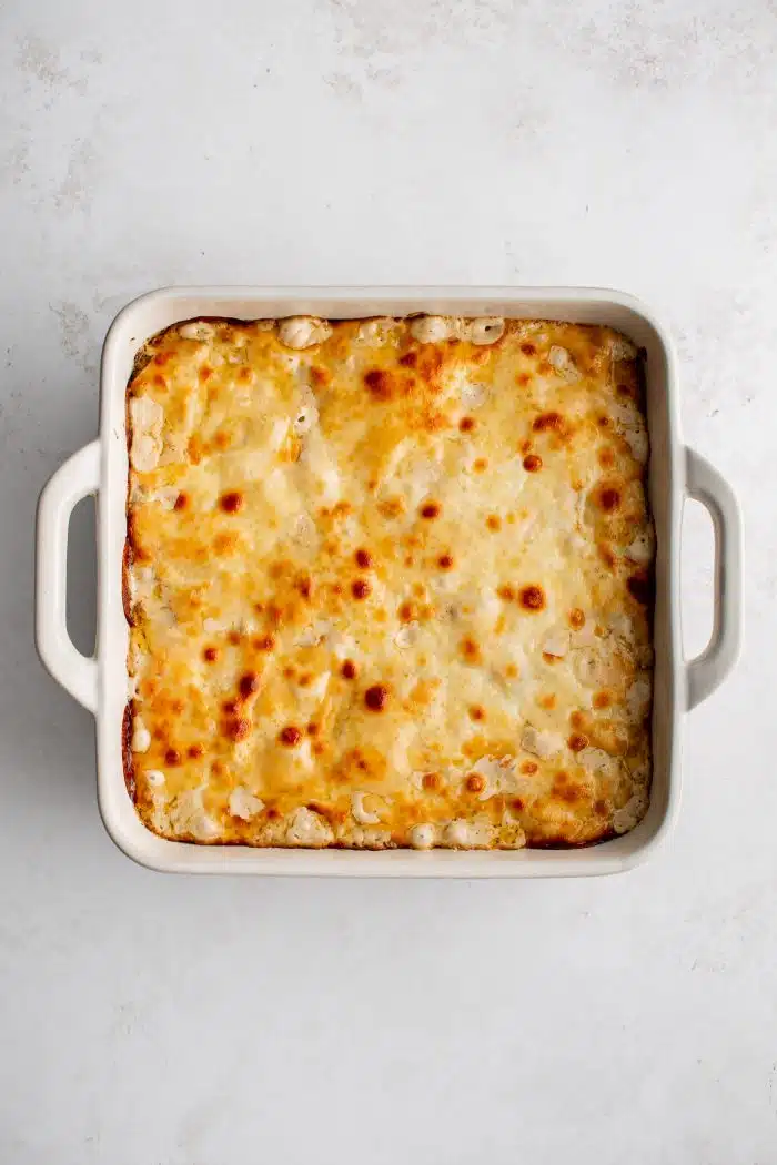 White square casserole dish filled with Philly cheesesteak casserole covered in gooey melted provolone cheese.