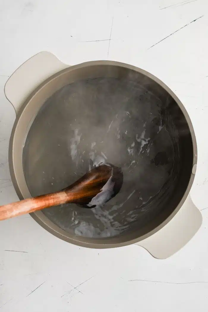 Wooden spoon swirling a pot of boiling water.