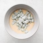 Flour-coated okra pieces added to the mixing bowl filled with whisked together buttermilk, egg, and hot sauce.