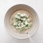 Straining the flour-coated okra from the bowl filled with whisked together buttermilk, egg, and hot sauce.