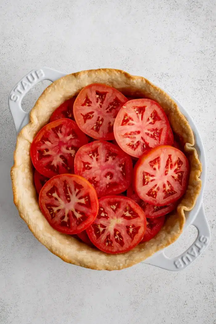 Sliced tomatoes in a par-baked pie crust.