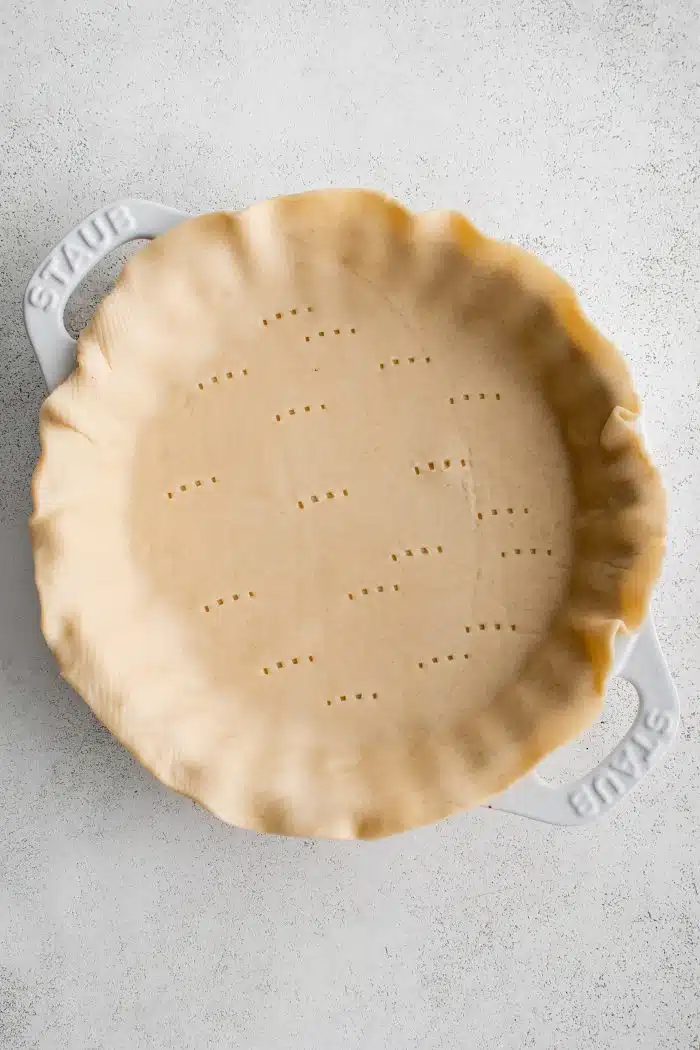 White pie dish filled with unbaked pie crust.