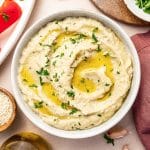 Square overhead photo of baba ganoush garnished with olive oil, parsley, and sesame seeds.
