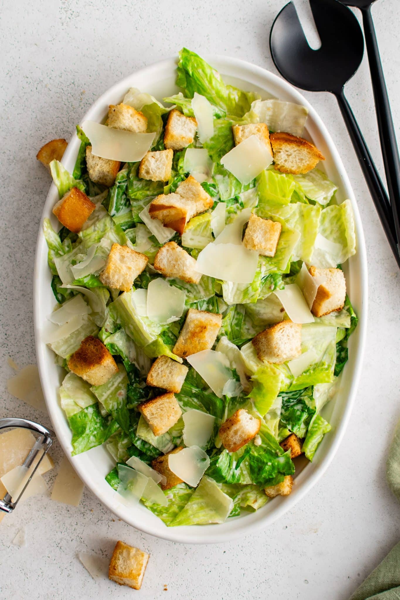 Oval salad plate filled with romaine lettuce tossed in homemade Caesar salad dressing, homemade croutons and shaved parmesan cheese.