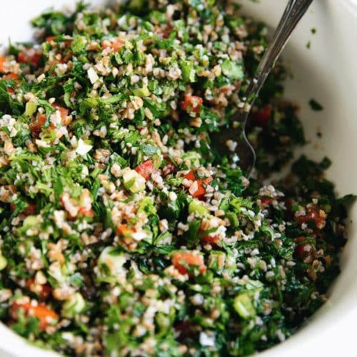 Bright green and fresh homemade tabouli in a white bowl.