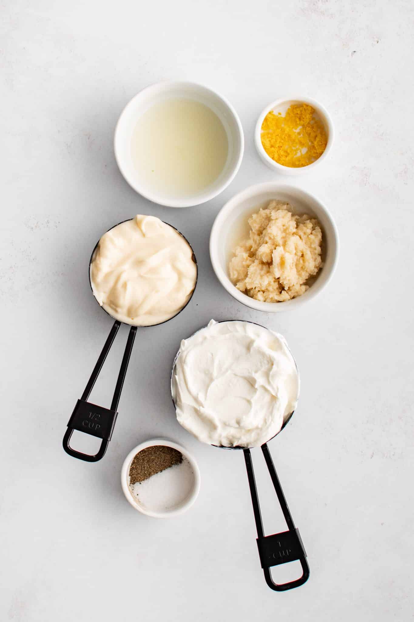 All of the ingredients for Homemade creamy horseradish Sauce presented in individual measuring cups and ramekins.