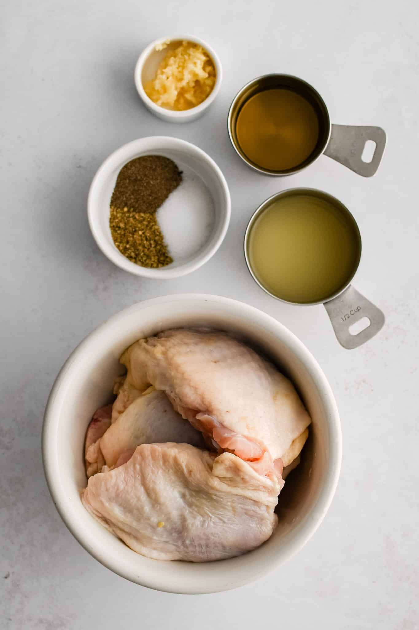 All of the ingredients for Greek lemon chicken thighs presented in individual measuring cups and ramekins.