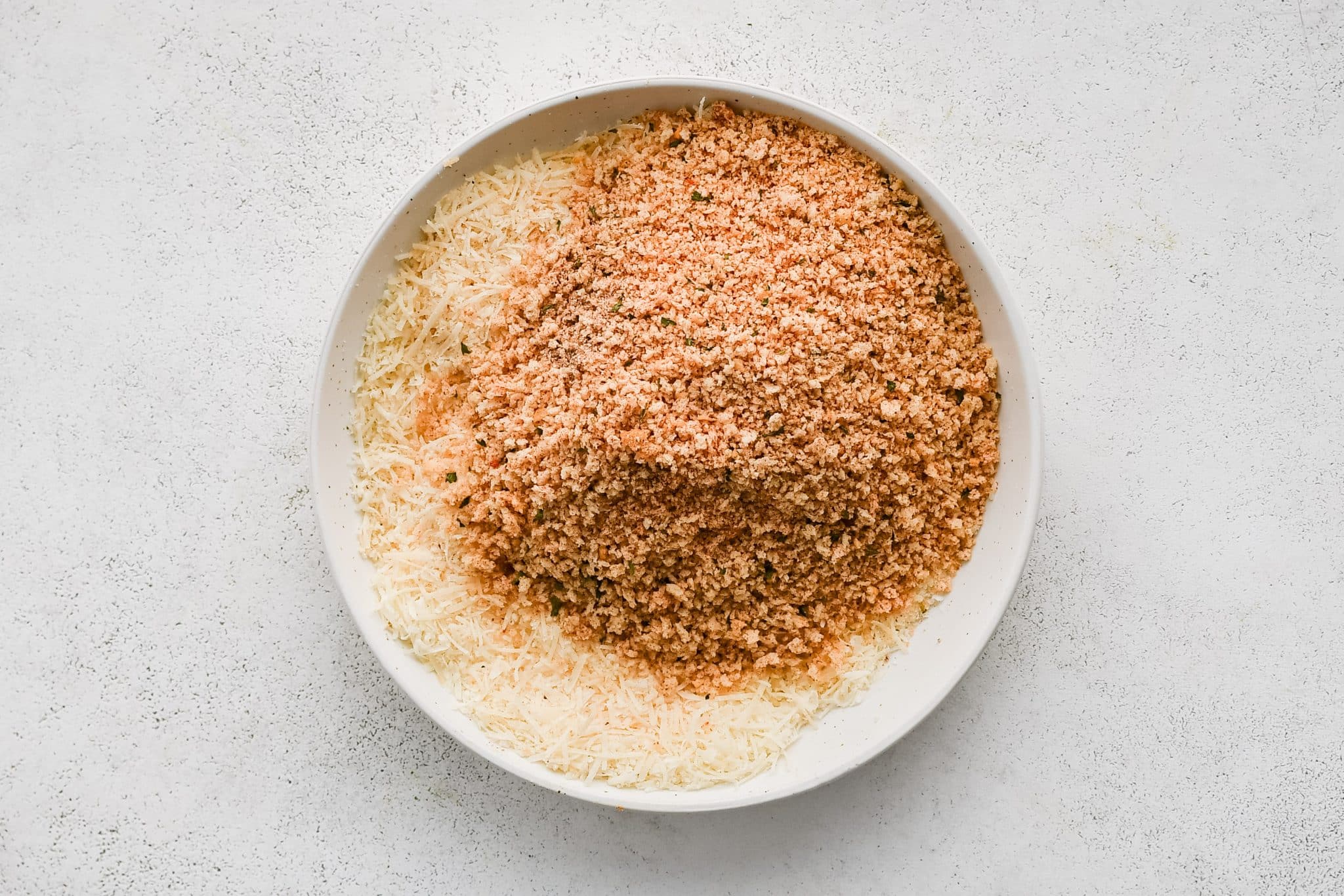Bowl filled with grated parmesan cheese and Italian-style panko breadcrumbs.