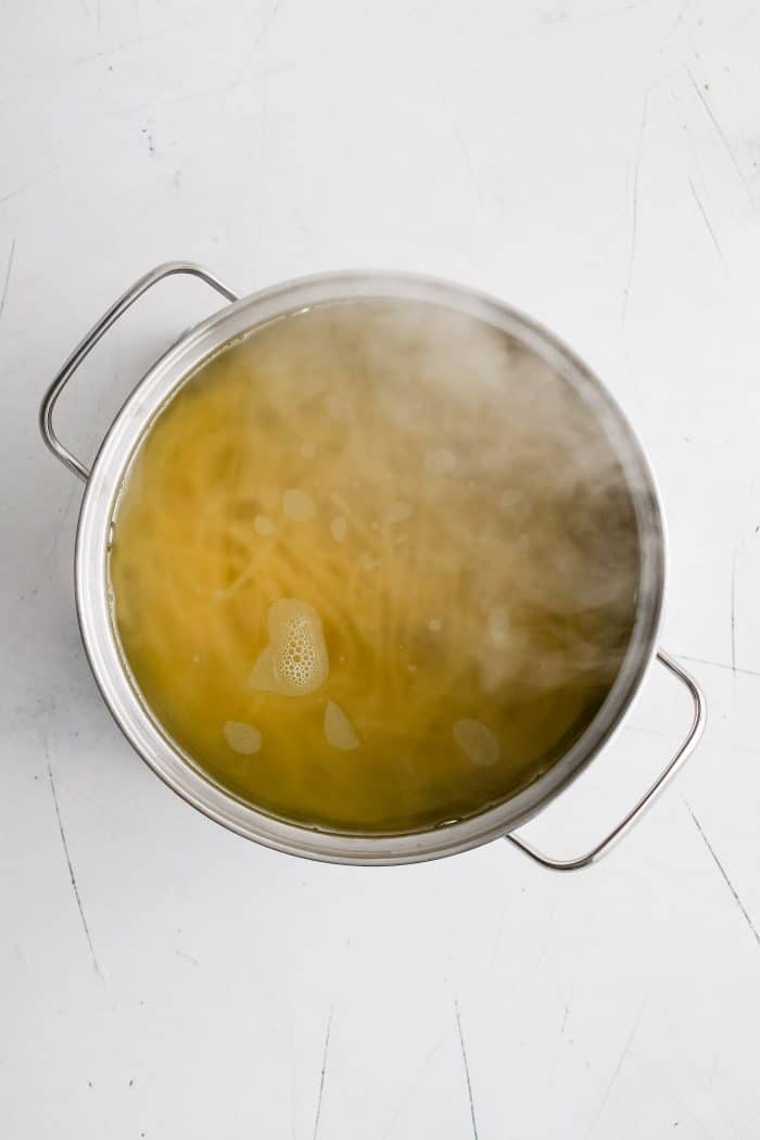 Spaghetti noodles cooking in a large pot of boiling water.