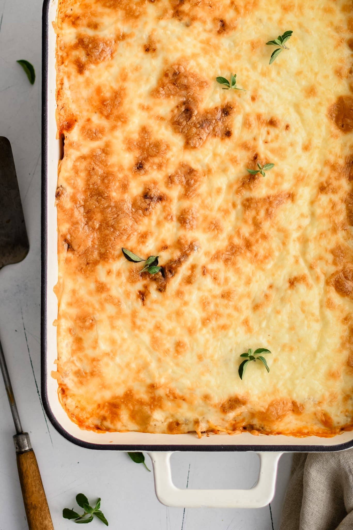 Large casserole dish filled with spaghetti casserole with a top layer of melted, golden, and bubbly mozzarella cheese.