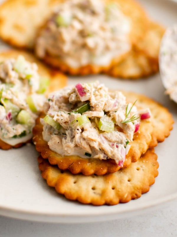 Small plate with golden buttery crackers topped with homemade canned salmon salad and garnished with fresh minced dill.