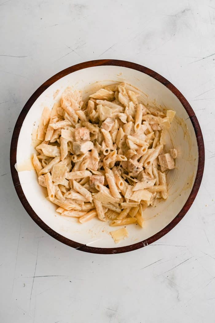 Large salad bowl filled chopped cooked chicken, cooked and cooled penne pasta, and parmesan cheese tossed in creamy Caesar salad dressing.