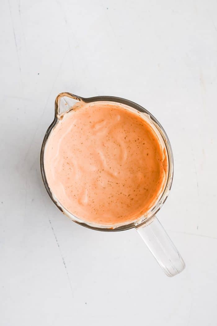 A glass pitcher filled with thick and creamy chipotle ranch dressing.